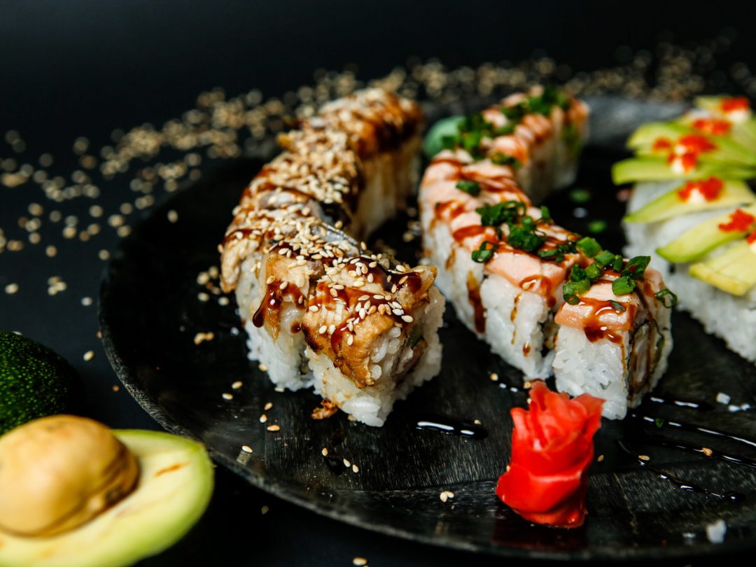lots of various types of sushi rolls topped with sesame seeds close-up view